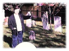 Patsy pointing to abandoned tombstones from Old St. Luke's Scottish Cemetery in Bathurst, New Brunswick, Canada